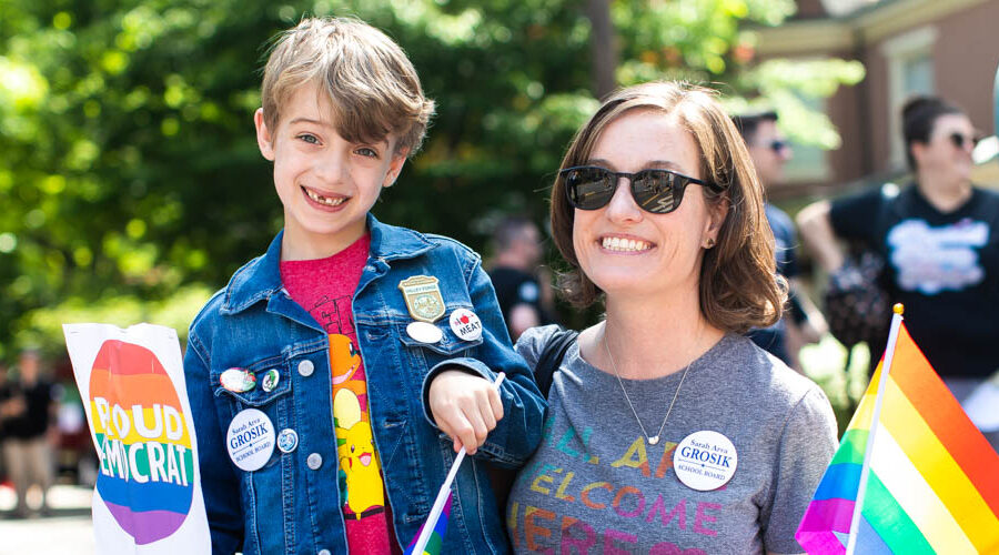 Mother and son smile for portrait during a parade holding a a sign that says Proud Democrat in Bucks County PA